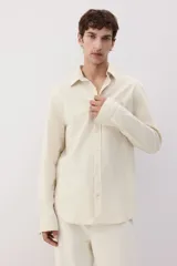Camisa color crema en mezcla de lino y algodón, de corte regular fit, manga larga con puños abotonados, cuello inglés, tapeta clásica, canesú en la espalda, bolsillo superior abierto y bajo redondeado.