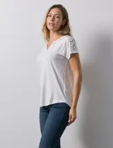 Blusa blanca de modal con cuello redondo y escote en V. Tiene apliques de crochet en el escote y los hombros.