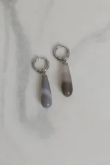 Par de aros colgantes con argolla de acero quirúrgico y dije en forma de lágrima de piedra natural gris con efecto degradado.