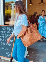 Bolso tote de cuero color marrón con asas trenzadas en marrón y rojo.