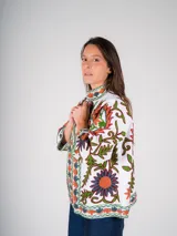 Chaqueta blanca de algodón con bordado floral multicolor de estilo Suzani. Tiene cuello mao, mangas 3/4 y cierre frontal con botones.