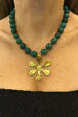 Collar de cuentas esféricas de piedra turquesa africana con dije de bronce en forma de flor.