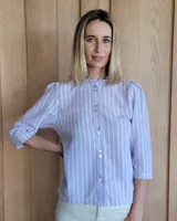 Camisa color beige claro con cuello con volados y mangas 3/4 abullonadas.