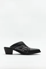 Zuecos negros de cuero sintético con punta fina, bordados en la capellada y taco cuadrado de 5cm de alto.