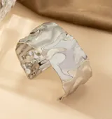 Brazalete rígido plateado con diseño irregular y textura martillada.