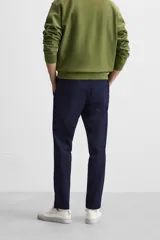 Pantalón negro de corte slim fit, confeccionado en tejido elástico. Cuenta con cintura elástica, bolsillos frontales y traseros de vivo. Cierre frontal con cremallera y botón.