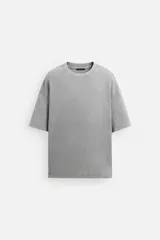 Camiseta gris de corte amplio, cuello redondo y mangas cortas. Tiene un efecto lavado que le da una apariencia única.