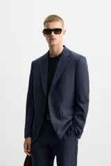 Blazer azul marino con sutil diseño de cuadros, corte regular fit, cuello con solapas de muesca, manga larga con puños abotonados, bolsillo de vivo en el pecho, bolsillos de solapa en la cadera, bolsillo interior, aberturas en la espalda y cierre frontal con dos botones.