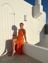 Vestido largo lila con escote halter cruzado en la espalda y falda tipo pareo con abertura lateral y nudo decorativo.