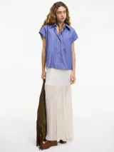 Camisa musculosa a rayas verticales azules y blancas, con cuello camisero, botones en la parte delantera y trasera, y lazo regulable en el cuello.