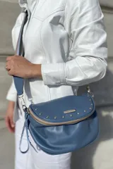 Bandolera de cuero celeste con correa de cinta regulable, forro de algodón, cierre central y bolsillo trasero con cierre.