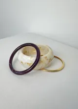 Set de tres pulseras rígidas: una color borgoña con efecto marmolado, una color crema con efecto marmolado y una dorada.