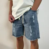 Bermuda de jean color negro con efecto desgastado y roturas, corte jogger arriba de la rodilla y cintura con cordón ajustable.