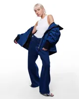 Pantalón de denim azul con corte sastrero de pierna ancha, tiro alto, cierre frontal invisible y pretina cruzada. Aplique de caballo/dragón en bronce hecho a mano y bordado negro del logo Temblad en la parte trasera.