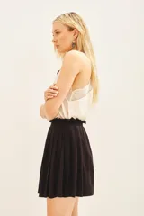 Minifalda negra estilo portafolio con tablas, cintura elastizada y broche metálico.