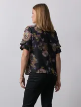 Blusa de gasa estampada con cuello a la base y escote en V. Tiene mangas cortas amplias con sobrecapas.