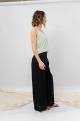 Pantalón negro de corte ancho y fluido, tiro medio con presillas para cinturón, bolsillos laterales funcionales y pinzas delanteras.