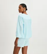 Blusa rosa de poliéster con escote en pico, botones delanteros, manga larga con puños elásticos y pliegues en los hombros.