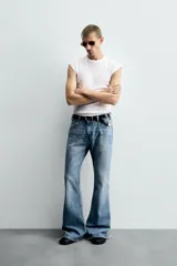 Pantalón de jean celeste, de tiro medio, corte ajustado en la parte superior y acampanado desde la rodilla. Tiene cinco bolsillos, efecto lavado y bajo irregular.