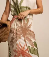 Vestido midi sin mangas, con cuello redondo, hombreras y lazo en la cintura. Presenta un estampado de cocoteros y aberturas en el bajo.
