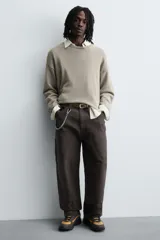 Zapatillas deportivas color crema con cordones, suela gruesa con diseño irregular y detalles en gris.