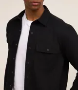 Camisa marrón de manga larga, confeccionada en sarga, con cuello inglés, abotonado delantero, bolsillos en el pecho con solapa y puños abotonados.