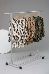 Camisa de viscosa con estampado retro en tonos marrón, beige, blanco y verde. Tiene cuello mao, mangas largas y corte asimétrico con la parte trasera más larga que la delantera.