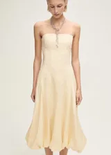 Vestido midi color crema, de lino, con escote strapless y falda con bajo abullonado.