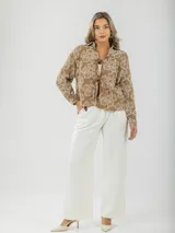 Blusa color crudo con bordados florales, cuello camisero y mangas largas.
