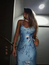 Vestido midi celeste con estampado floral en tonos azules y blancos, de breteles finos y corte al cuerpo.