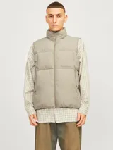 Chaleco acolchado sin mangas color gris topo, con cuello alto y cierre de cremallera. Tiene bolsillos frontales y relleno de fibra sintética.