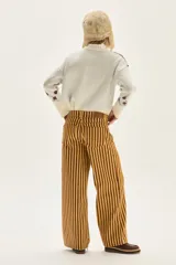 Pantalón de jean tiro medio, corte wide leg, con estampado de rayas verticales en tonos amarillo mostaza y marrón oscuro.