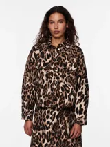 Camisa animal print con estampado de leopardo en tonos marrones y beige. Tiene cuello camisero, mangas largas con puños abotonados, cierre frontal con botones y dos bolsillos de parche en el pecho.