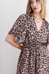 Vestido midi con estampado animal print, mangas cortas amplias, escote en V, cintura elastizada tipo nido de abeja, tajo central y ruedo asimétrico en picos.