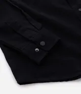 Camisa de manga larga color marrón, confeccionada en sarga de algodón, con cuello inglés, botones frontales y dos bolsillos de parche con solapa y botón en el pecho.