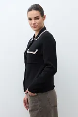 Chaqueta de tejido color terracota/lacre, con cuello y bordes de bolsillo en blanco con textura de punto. Posee cierre frontal de botones y manga larga.