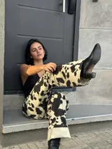 Pantalón de tiro alto color beige con estampado de manchas de vaca en marrón oscuro.