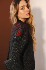 Cárdigan tejido con lurex, con cuello redondo, manga 3/4 y cierre frontal con botones forrados. Diseño con rayas verticales en tonos verde, azul y violeta sobre fondo negro con brillo.