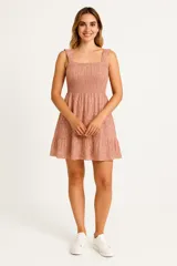 Vestido corto color rosa con estampado floral, breteles anchos y escote recto. Presenta frunces en el busto y falda con volados.
