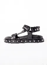 Sandalias marrones con textura de piel de cocodrilo, plataforma plana con tachas plateadas y tiras anchas con hebilla ajustable.