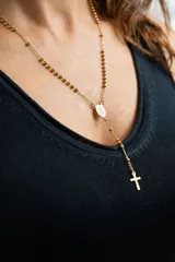 Collar tipo rosario dorado con cuentas y dije de cruz.