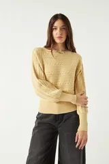Sweater color amarillo claro, tejido en punto trenzado con cuello redondo y mangas largas abullonadas.