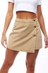Falda short color beige con diseño cruzado y botones decorativos.