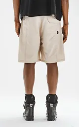 Bermuda color beige con cintura elástica, cordón de ajuste y cinturón negro con hebilla plástica. Tiene bolsillos delanteros y bolsillos cargo con solapa.