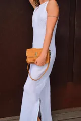 Minibag tipo acordeón, color negro con acabado brillante o glitter. Presenta solapa frontal con cierre metálico dorado de giro. Incluye correa larga ajustable y correa corta de mano.