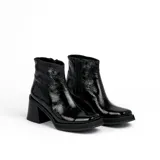 Bota corta de cuero negro, con taco cuadrado y punta cuadrada. Presenta un panel texturizado en el talón y cierre lateral.