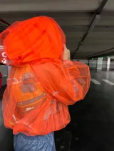Conjunto de campera y pantalón. La campera es de voile estampado con personajes de la película Cars, tul y dry-fit, y symphony naranja. El pantalón es de tela engomada brillante celeste.