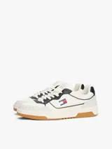 Zapatillas bajas de cuero napa color blanco con detalles en negro y gris. Presentan una suela cupsole de goma color caramelo, paneles con mezcla de texturas, perforaciones de ventilación en la puntera y el parche clásico de Tommy Jeans en el lateral.