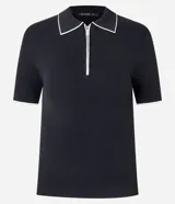Blusa de punto negra de manga corta, ajustada al cuerpo, con cuello polo y ribetes blancos contrastantes. Presenta un cierre frontal con cremallera en el escote.