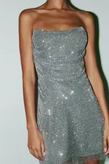 Vestido corto plateado de tejido tipo red con aplicación de strass, escote recto y hombros descubiertos.